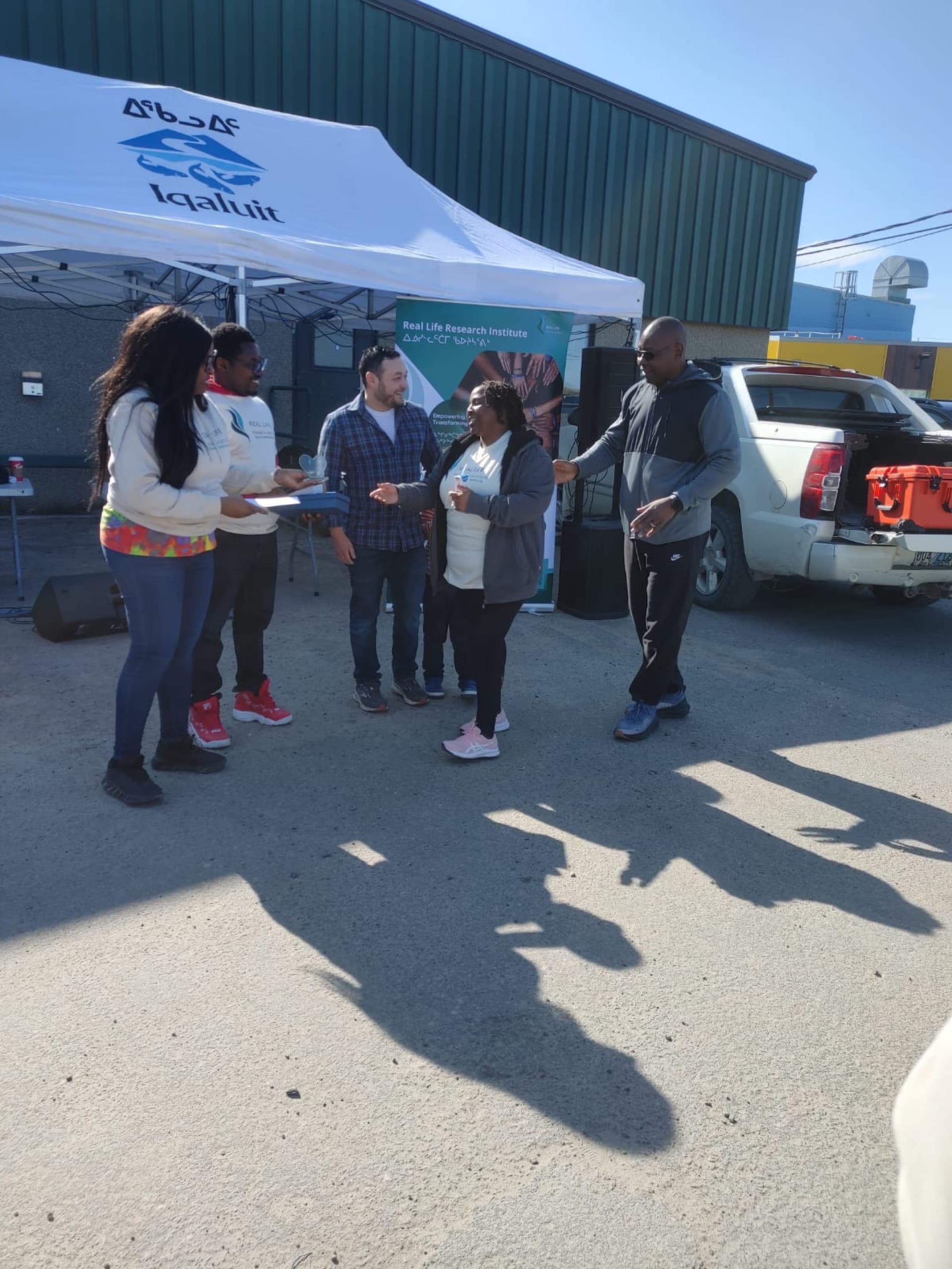 RLRI team presenting an award to a community member under the City of Iqaluit tent